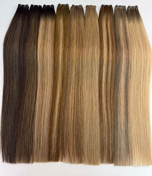 QOGH flat weft hair extensions in natural shades laid flat, showing the stitched weft track